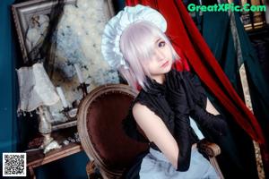 A woman in a maid outfit sitting on a chair.