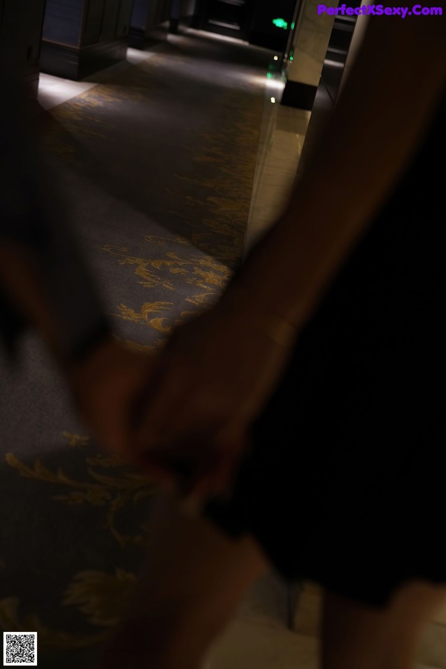 A person holding the hand of another person in a hallway.