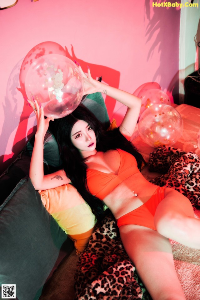 A woman laying on a bed holding a bunch of balloons.
