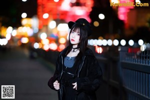 A woman standing on a sidewalk at night in the city.