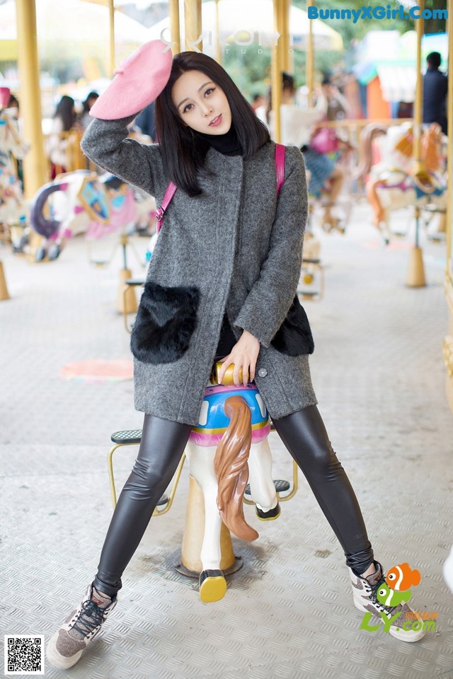 A woman sitting on a carousel with a pink hat.