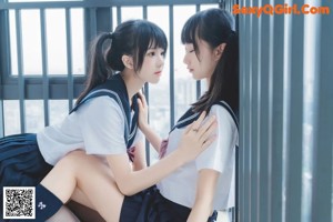 A couple of girls in school uniforms standing next to each other.