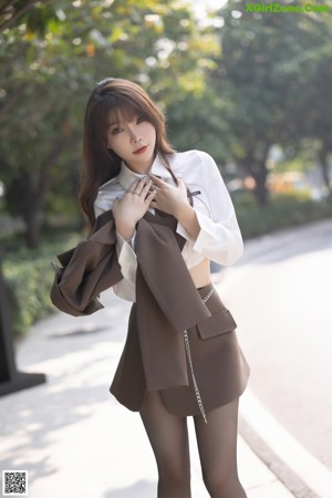 A woman in black stockings and a white shirt is sitting on a table.