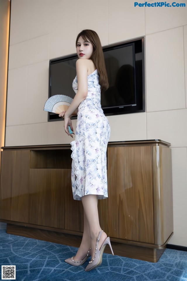 A woman in a white dress holding a fan.