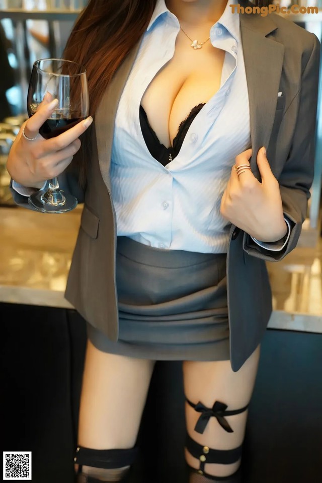 A woman in a business suit holding a glass of wine.