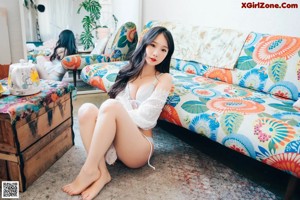 A woman in a white lingerie sitting on a white chair.