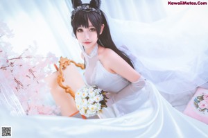 A woman in a wedding dress sitting on a bed.