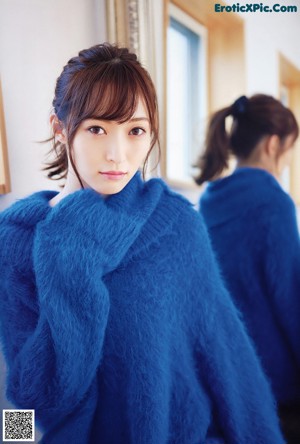 A woman in a blue sweater is posing for a magazine.