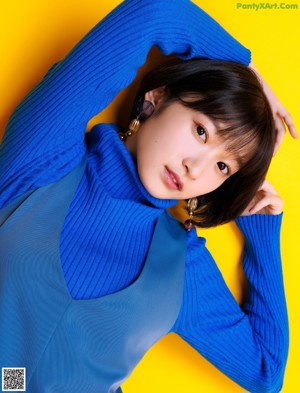 A woman in a blue sweater is posing for a magazine.