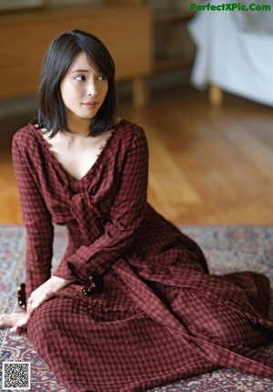 A woman sitting on a couch with her hand on her chin.