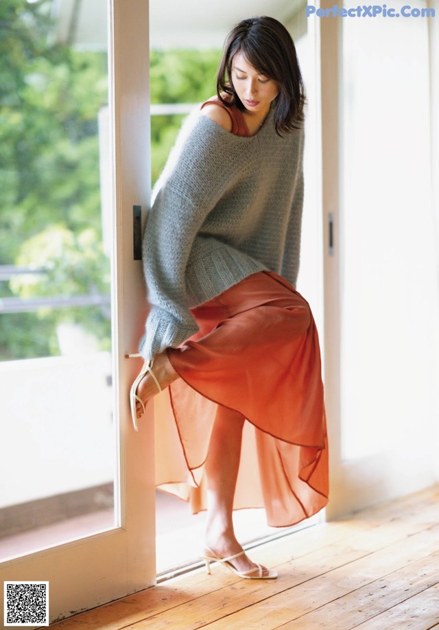 A woman leaning against a door in a room.