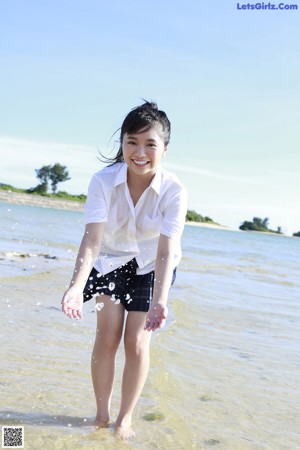 A woman in a black bikini laying in the water.