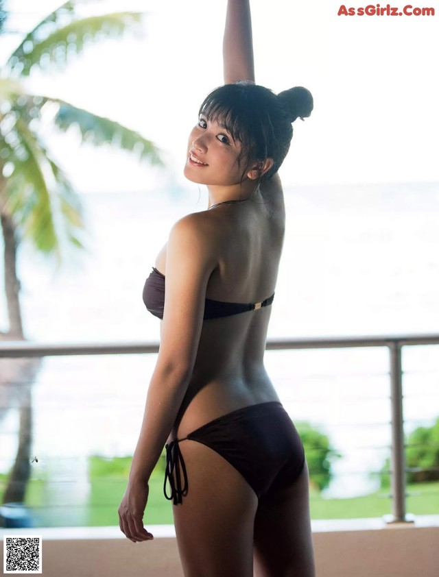 A woman in a black bikini standing on a balcony.