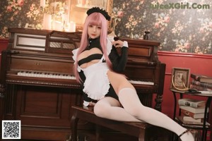 A woman with pink hair sitting on top of a piano.