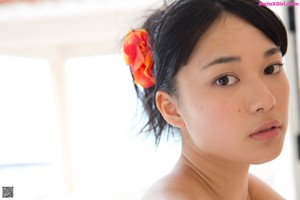 A woman in a black bikini leaning against a wall.