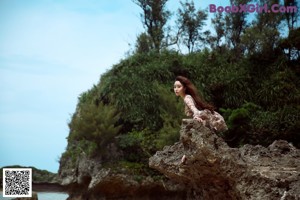 A woman sitting on top of a rock next to another woman.