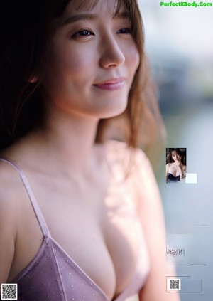 A woman in a white bathing suit leaning against a window.