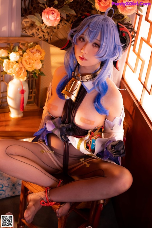 A woman with blue hair sitting on a chair.