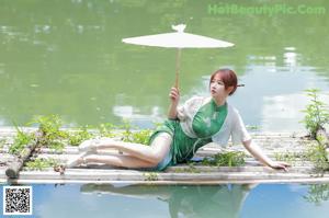 A woman in a green dress leaning against a window.