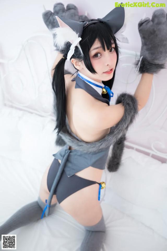 A woman in a cat costume is posing on a bed.