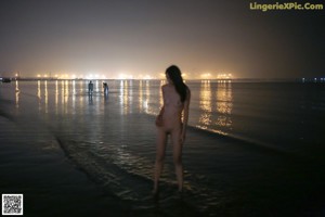 A naked woman standing on top of a lush green field.