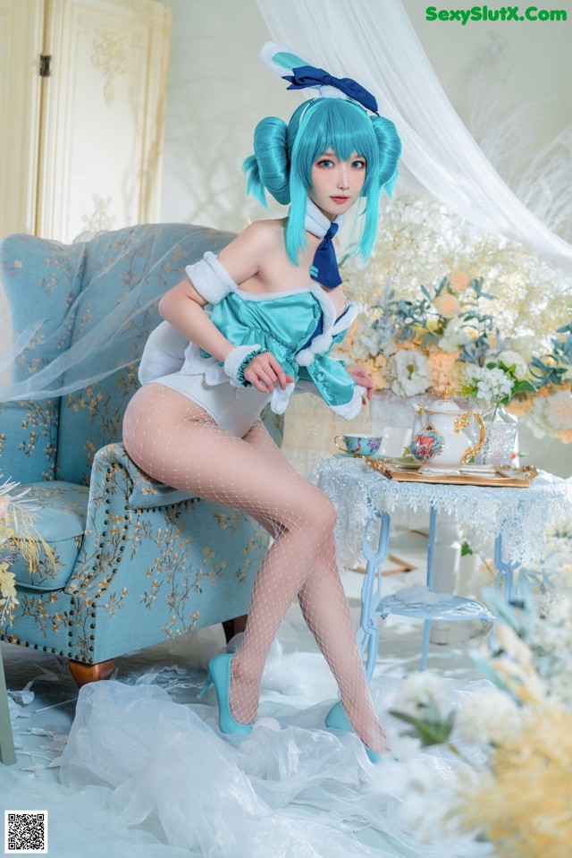 A woman in a blue and white outfit sitting on a blue chair.