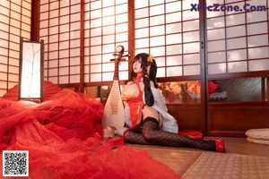 A woman in a red and black outfit sitting on a bed.