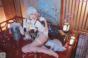 A woman in a white and black outfit sitting on a wooden floor.
