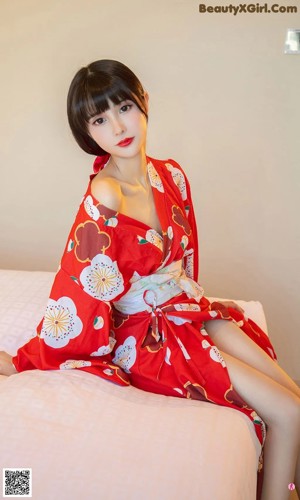 A woman in a red kimono sitting on a table.