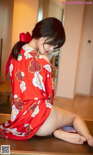 A woman in a red kimono sitting on a bed.