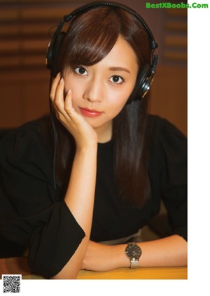 A young woman wearing headphones sitting in a chair.