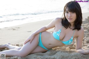 A woman in a blue bikini standing on a beach.