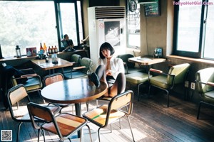 A woman sitting at a bar pouring a drink.