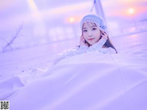 A woman sitting on top of a bed next to a plant.