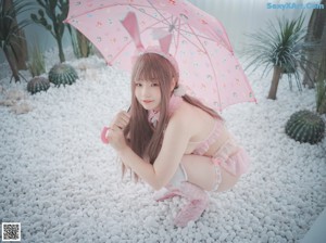 A woman in a pink lingerie sitting on a white bench.