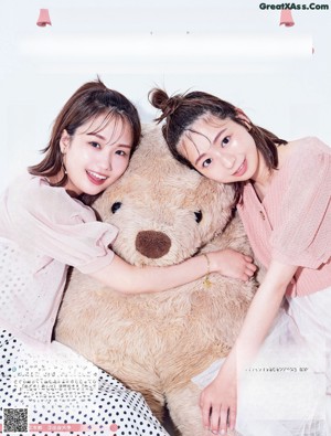 A couple of women laying on top of a bed of flowers.