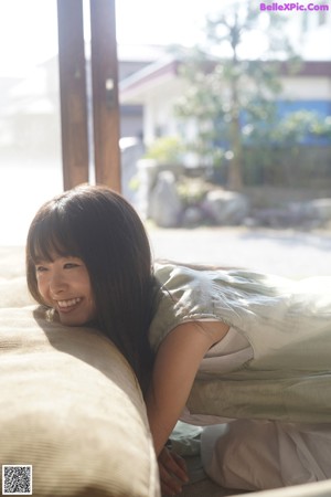 A young woman with long brown hair and bangs smiles at the camera.