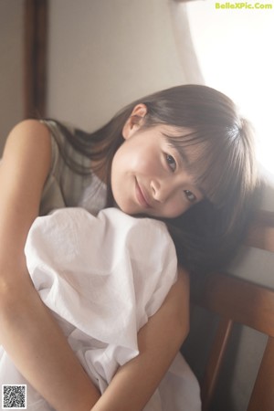 A woman sitting on a wooden bench next to a window.