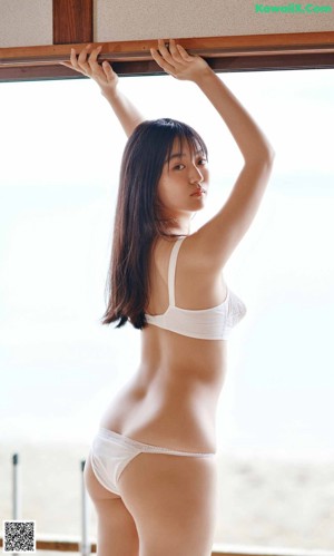 A woman in a blue and white bikini standing on a beach.